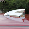 A silver shark fin car antenna with a heart shape is mounted on a red car body.