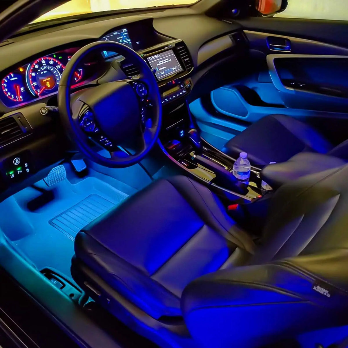 Interior view of a car showing blue ambient lighting and a steering wheel with digital displays.