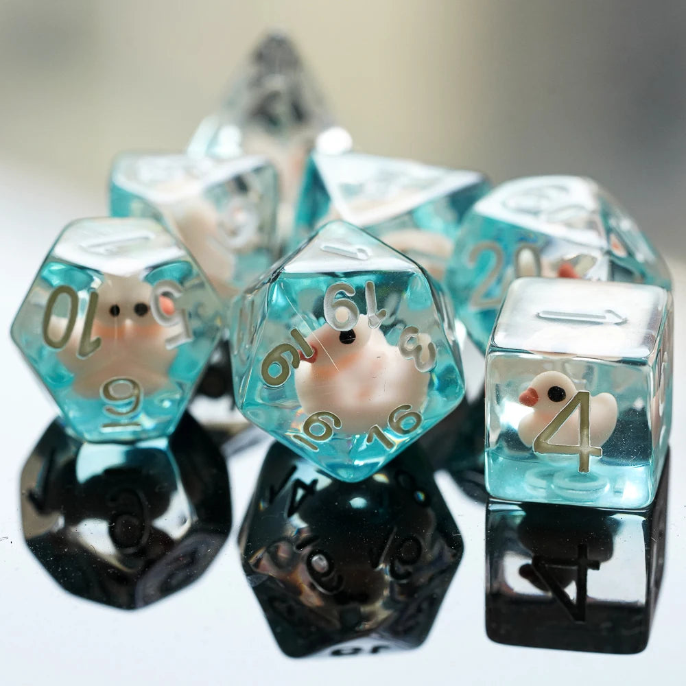 A collection of clear blue resin dice shaped like animals, including a duck, resting on a reflective surface.
