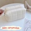 A white quilted portable makeup bag with a zipper is displayed on a white surface.