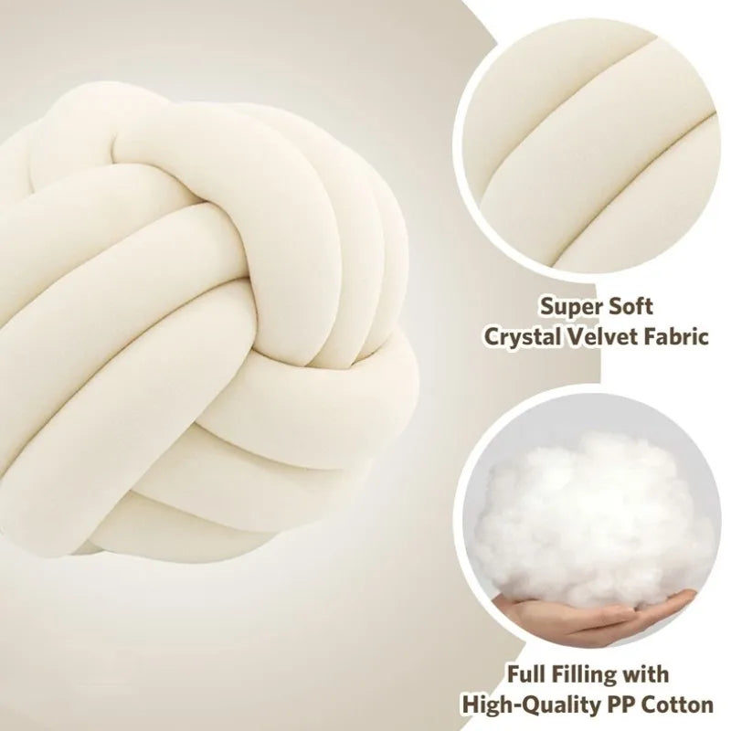 A close-up of a cream-colored, hand-knotted velvet throw pillow showing its texture and soft filling.
