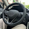A close-up view of a black steering wheel with a leather cover installed inside a car.