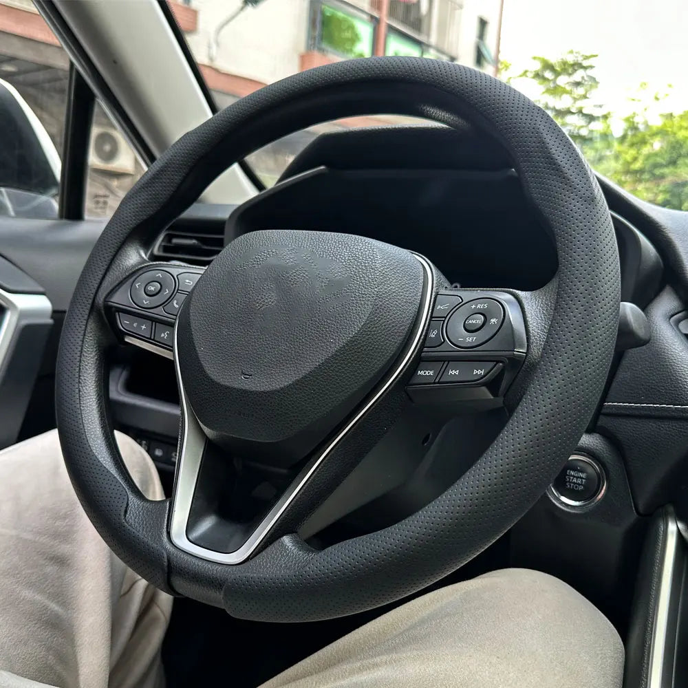 A close-up view of a black steering wheel with a leather cover installed inside a car.