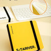A yellow S&TARIVER sketchbook with a black cover, shown next to a white laptop and an art marker.