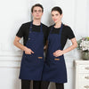 A man and a woman standing side by side wearing navy blue adjustable cotton aprons.