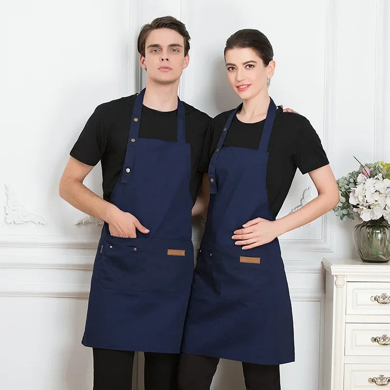 A man and a woman standing side by side wearing navy blue adjustable cotton aprons.