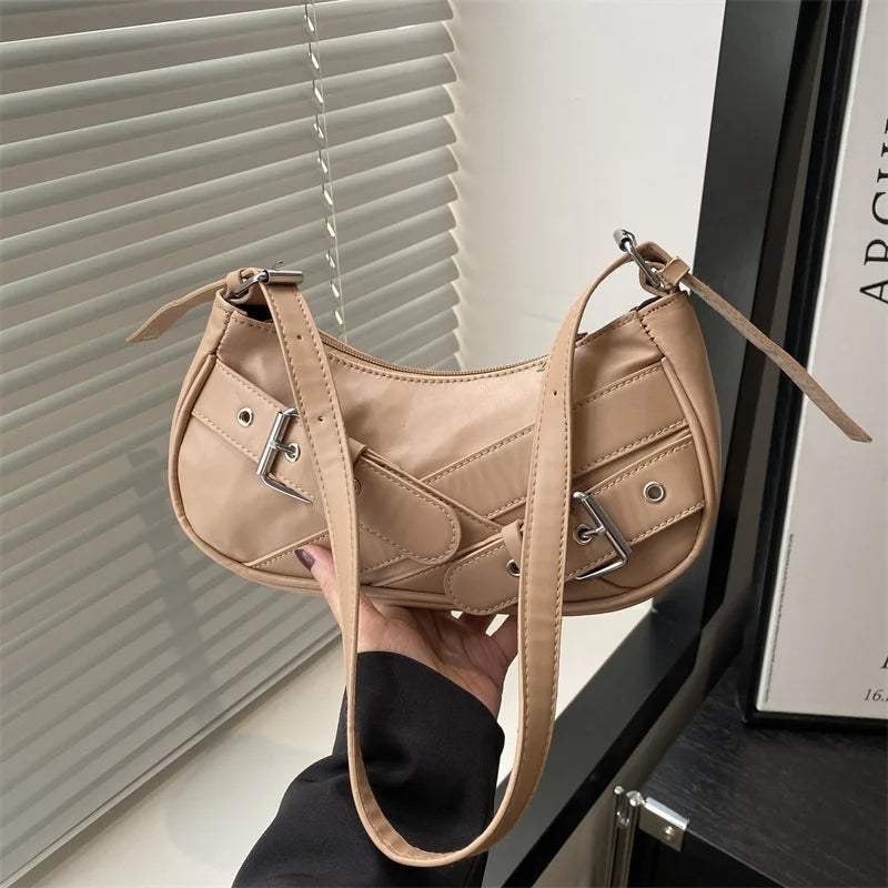 A light tan Y2K vintage PU leather crossbody bag is held by a hand against a window blind.