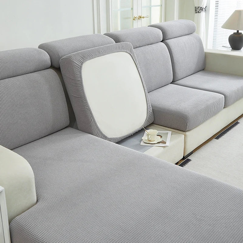 A light gray Jacquard stretch sofa slipcover with a white back cushion and non-slip grip.