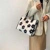 A woman holds a faux fur leopard print tote bag with black trim against a white background.