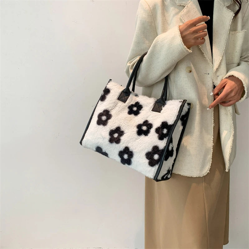 A woman holds a faux fur leopard print tote bag with black trim against a white background.