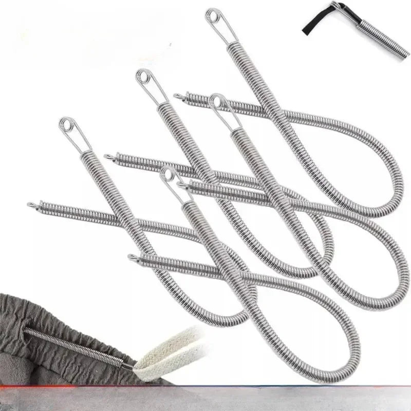 A set of silver spring drawstring needle threader tools lying on a gray fabric with a white cotton swab.