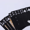 A stack of black playing cards showing the numbers 10 through Jack, with gold accents.