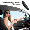 A woman is driving a car with a rain cover installed over the rear reversing camera.