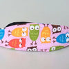 Pink fabric sleeping headrest featuring colorful owl designs for a baby car seat.