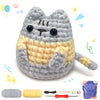 A finished gray and yellow cat amigurumi crochet toy next to yarn and tools.