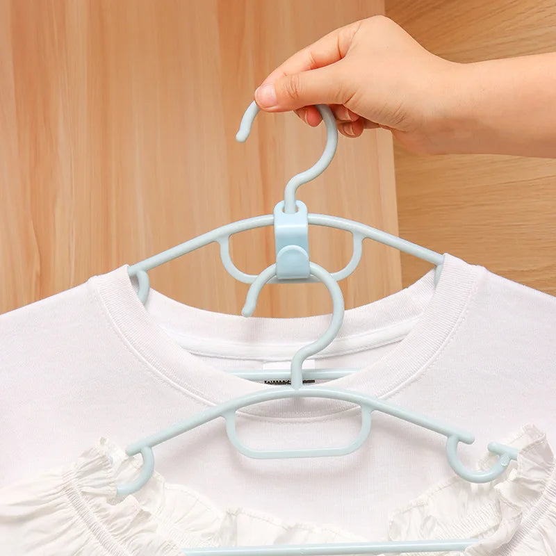 A hand is hanging a white shirt onto a light blue cascading hanger with connector hooks.