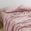 Soft pink pure linen bed sheet set with folded fabric and pillows