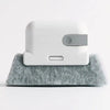 A white multi-surface gap cleaning brush with a silver pad resting on a gray felt surface.