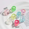 A collection of clear and colored acrylic alphabet beads of various sizes displayed on a white plate.