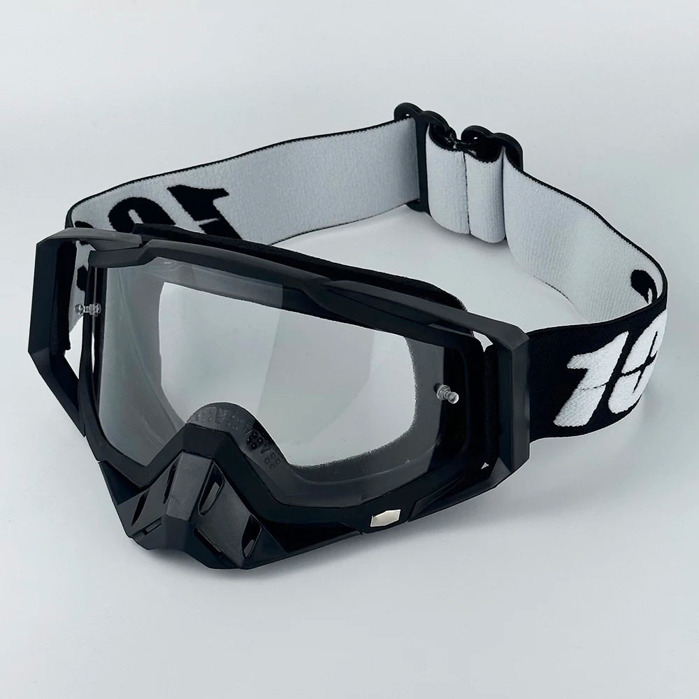 Black motorcycle goggles with a white strap are displayed against a white background.