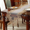 A dark wood table is set with an embroidered mesh lace table runner featuring intricate gold detailing.