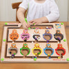 A wooden magnetic color sorting maze board for kids with various colored balls and a child interacting with it.