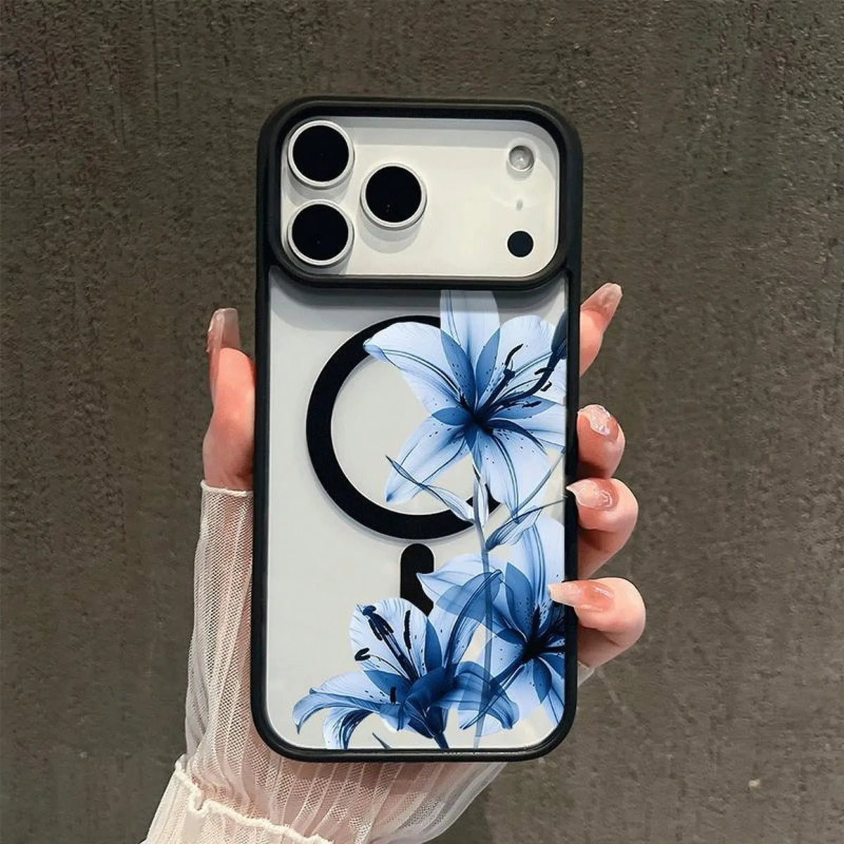 A hand holds a phone featuring a blue lily design on a clear case with a magnetic back.