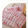 Pink and white checkered plush winter comforter or quilt draped on a bed.