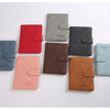 Une collection de porte-passeport en cuir de différentes couleurs : rouge, gris, noir et beige.