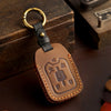 A brown leather key fob case with a brass ring attached, featuring an embossed logo.