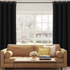 A living room features a beige sofa, a wooden coffee table, and black blackout curtain panels framing a window.