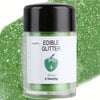 A glass jar of green edible glitter powder labeled Edible Glitter with a green apple illustration on a green background.
