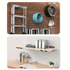 A collection of heavy-duty metal storage hooks and a tire mounted on a brick wall.