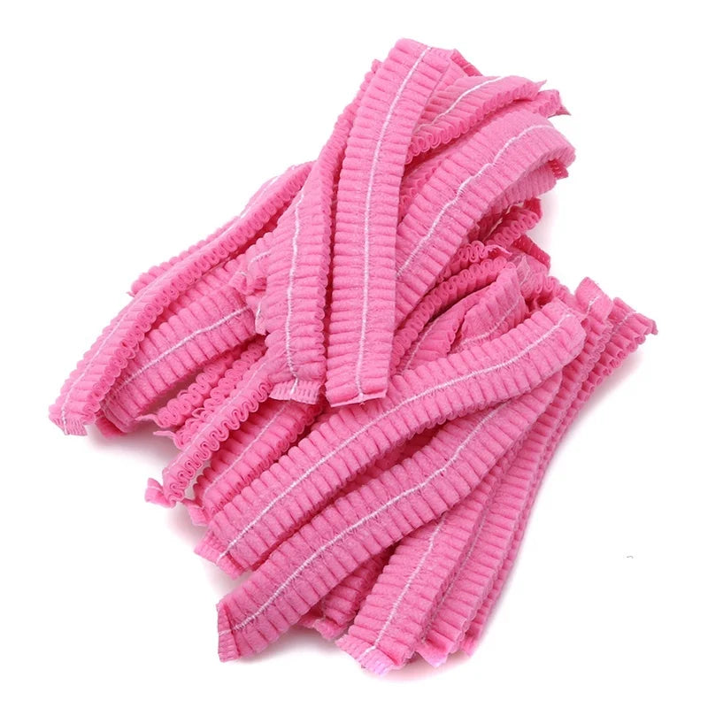 A stack of pink disposable non-woven hair net caps with ribbed texture.