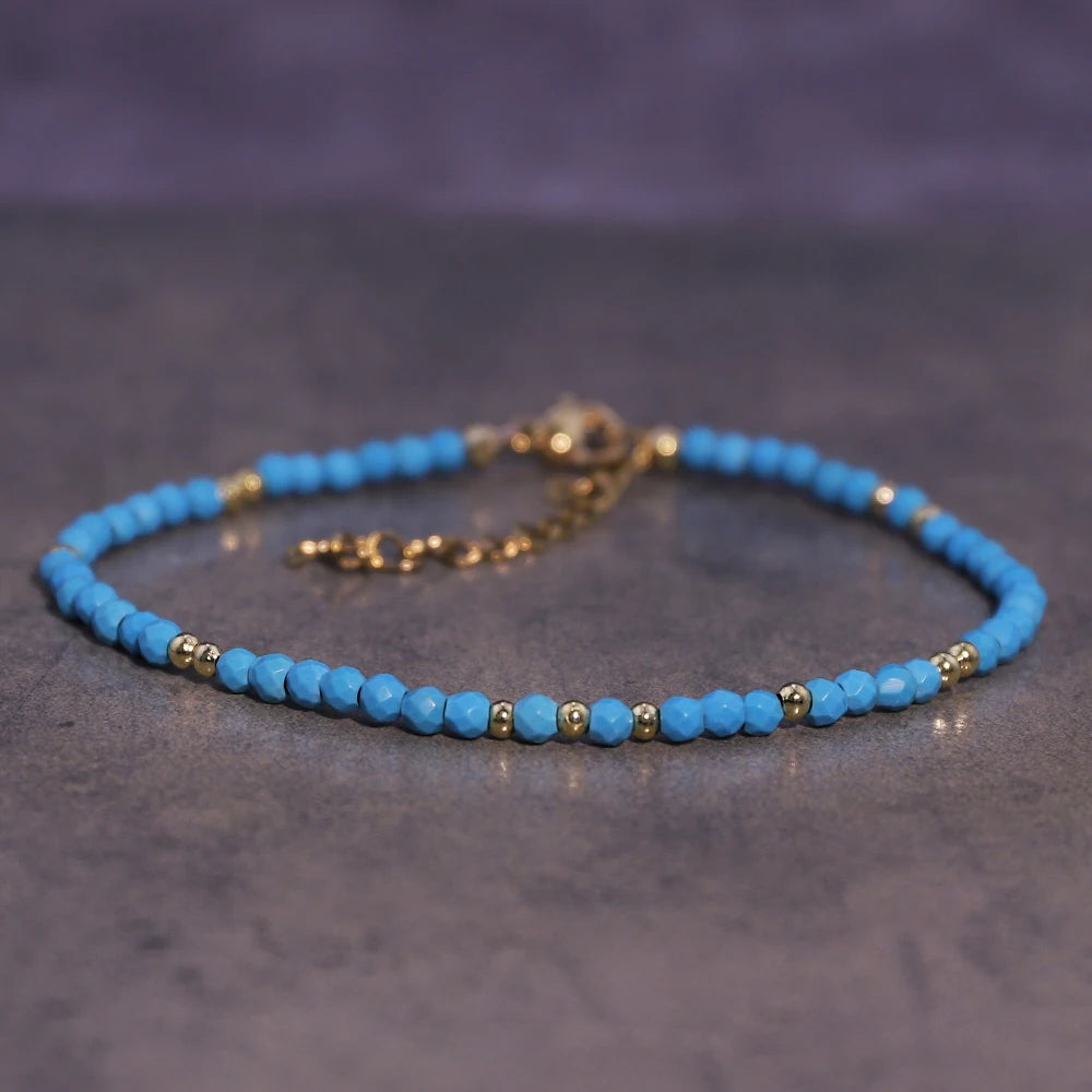 A bracelet made of small, light blue natural crystal beads strung on a gold-toned cord.