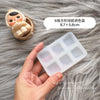 A hand holds a silicone paint palette tray with multiple wells, next to a small figurine.