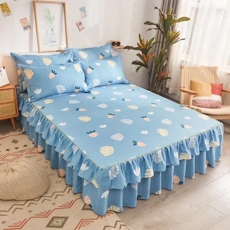 Une jupe de lit imprimée bleu clair à bords froncés et des oreillers sur un lit.