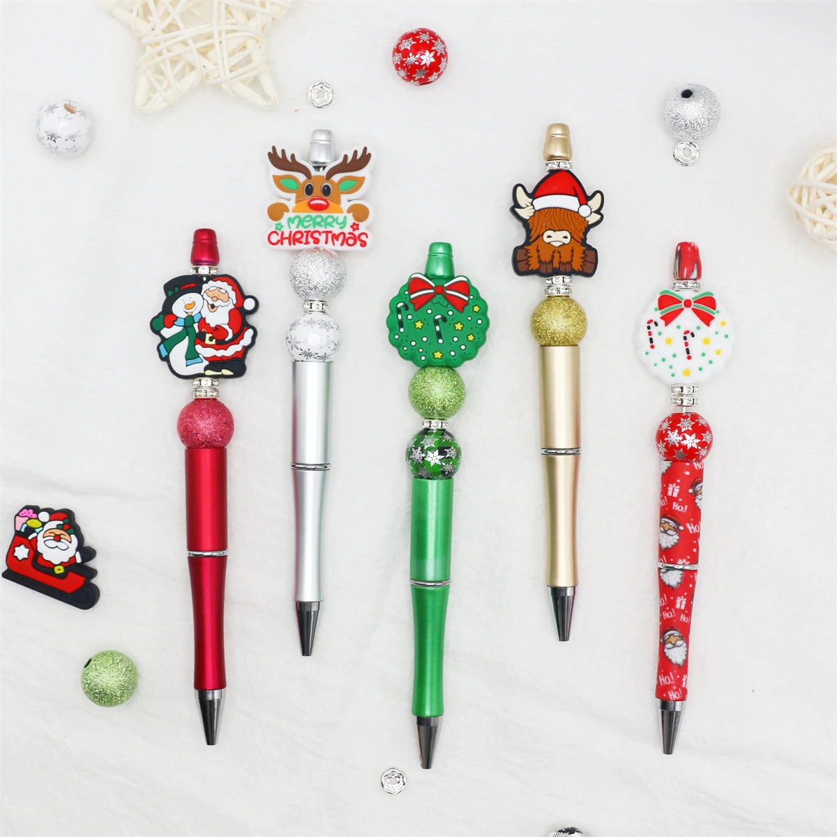 A craft kit featuring a beaded ballpoint pen with a Christmas theme, including various bead decorations and a festive topper.