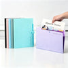A hand is pulling a stack of colored accordion document folders from a purple folder, showing the interior pages.