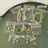 Clear self-sealing jewelry storage bags containing various items like earrings, bracelets, necklaces, and rings.