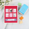 A red envelope featuring various floral and silhouette postage stamps, alongside a light blue embossing punch.