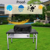 A black heavy-duty BBQ grill cover with a drawstring closure is placed on a metal table outdoors.