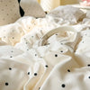 A close-up of a cream-colored polka dot bedding set with a duvet cover and pillow, showing soft folds.