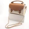 A tan and cream leather purse with a metal chain strap resting on a white box.