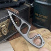 A compact stainless steel neck knife is shown resting on a tan glove and next to a dark box.