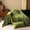 A moss green chenille sofa throw draped over a light-colored surface.