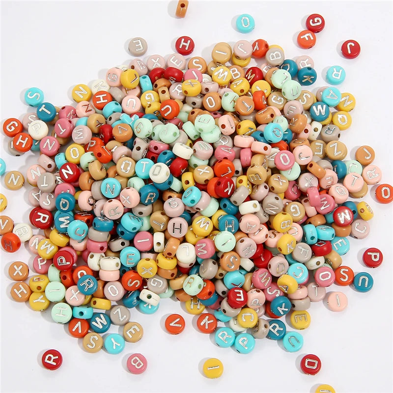 A scattered collection of colorful acrylic alphabet letter beads for jewelry making