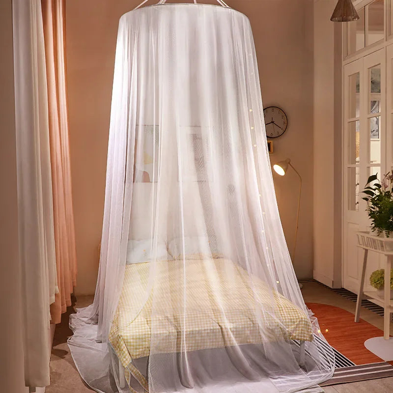 A romantic canopy mosquito net draped over a double bed in a light-colored room.