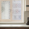 A close-up of a light pink window with decorative frosted privacy film featuring a geometric pattern.