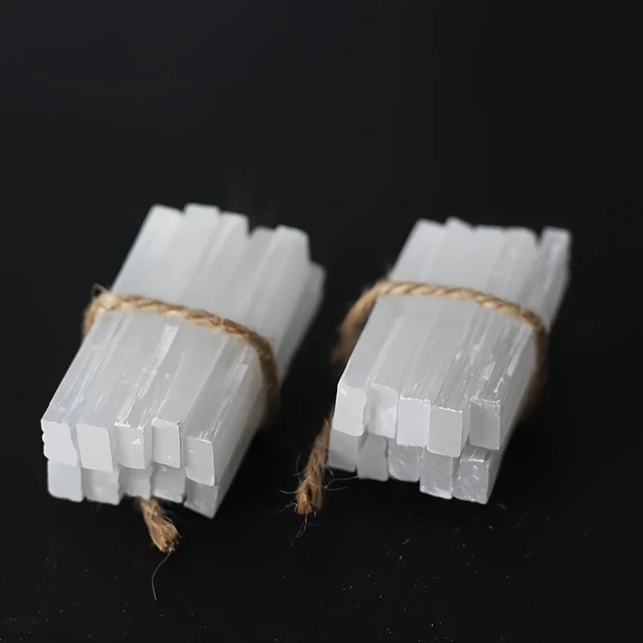 Two white selenite crystal wands tied with natural twine against a dark background